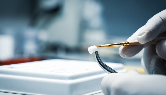 A lab worker processing a dental crown