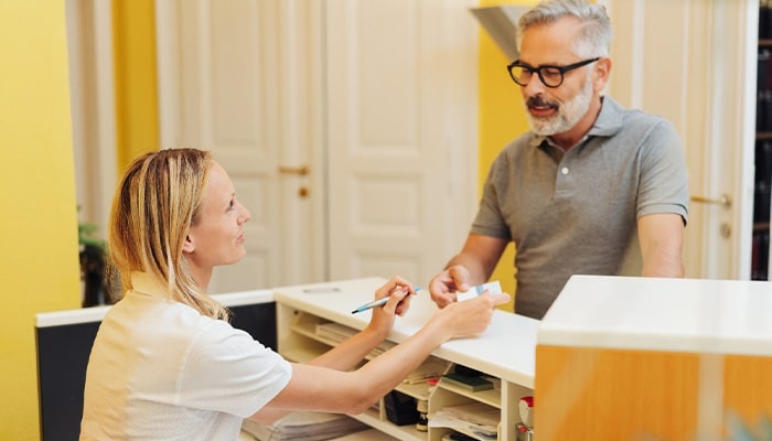 A middle-aged man paying the cost of dental crowns