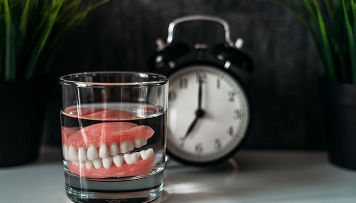 dentures in a glass of water on a nightstand