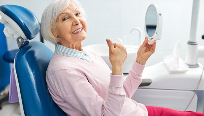 senior woman sitting in dental chair and smiling