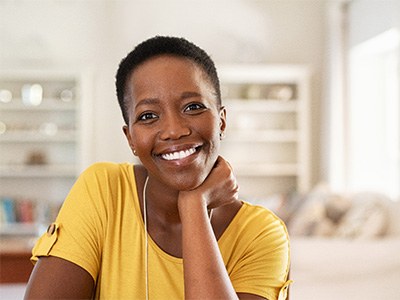 Woman in yellow shirt smiling at home