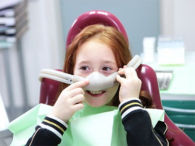 Child smiling while touching nasal mask