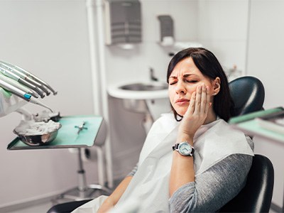 Woman with toothache sitting in treatment chair