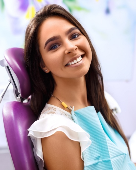Woman in dental chair grinning before a smile makeover