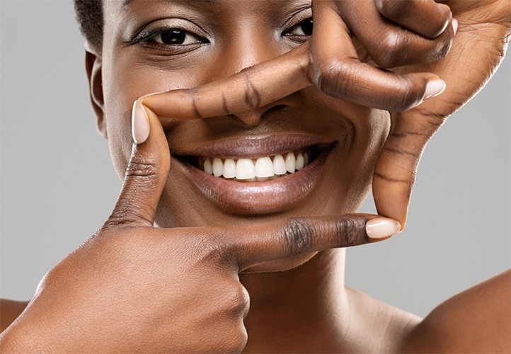 Woman framing her bright smile with 4 fingers