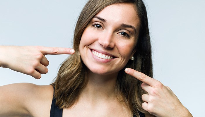 Woman pointing to her smile