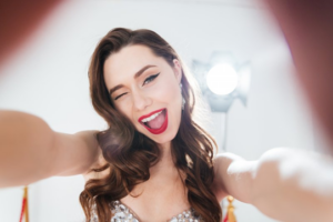 Young woman smiling brightly as she takes a selfie in the spotlight